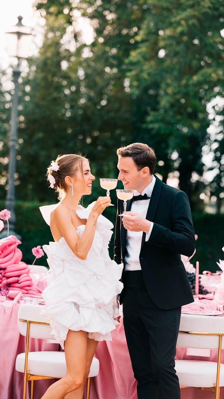 Woman in a short ruffled white wedding dress and man in a tuxedo.