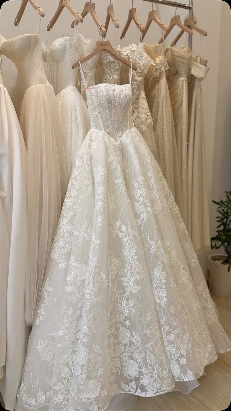 White strapless ballgown wedding dress with bold floral lacework hanging in a bridal shop