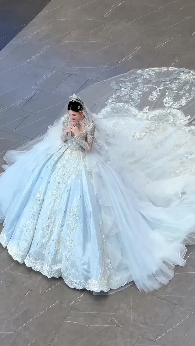 Woman in a voluminous light blue lace wedding gown with a long train.