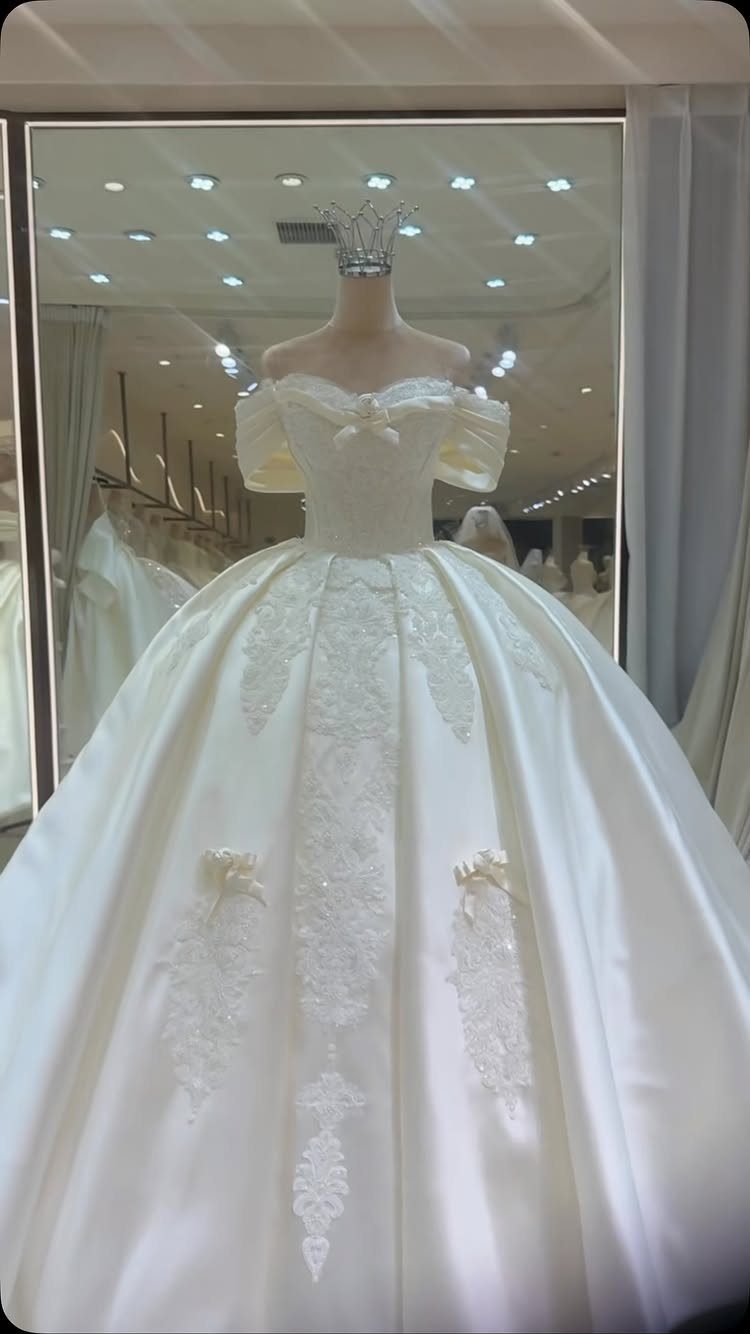 White satin off-the-shoulder princess wedding gown with voluminous skirt and lace embroidery.