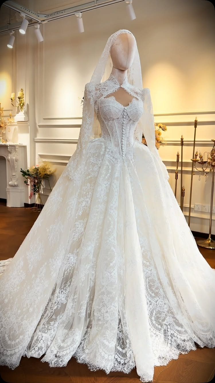 White lace princess wedding gown with a voluminous skirt and veil on a mannequin.