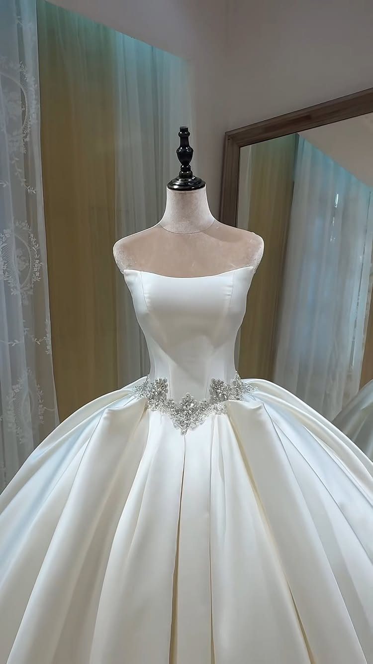 White satin ballgown wedding dress with sparkling waist embellishments on a mannequin.