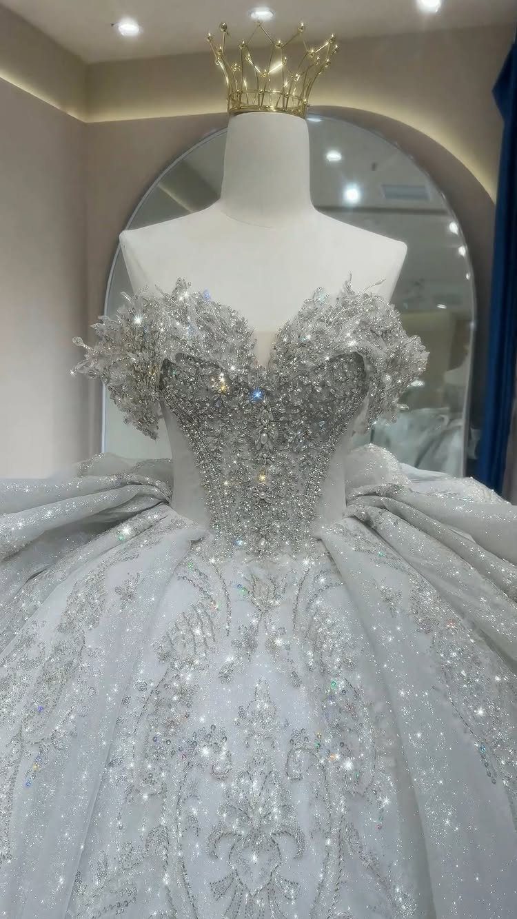 Sparkling silver princess wedding gown with a voluminous skirt and gold crown.