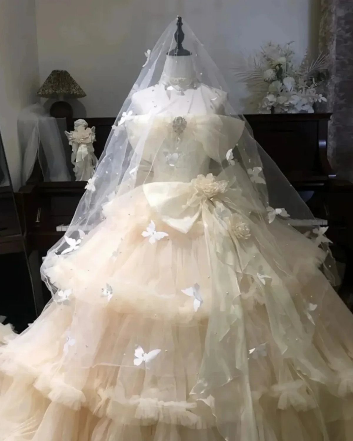 Voluminous cream wedding gown with tiered tulle skirt and butterfly details on mannequin