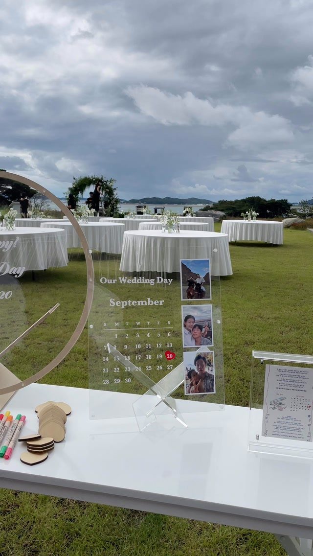 Acrylic wedding guest book calendar with wooden tokens on a white outdoor table