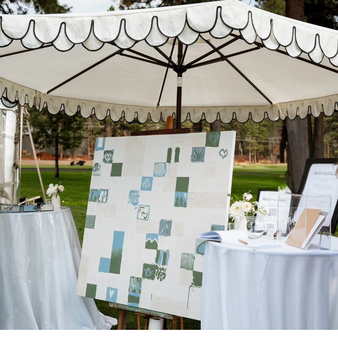 White canvas on an easel with green and blue painted squares under an umbrella.