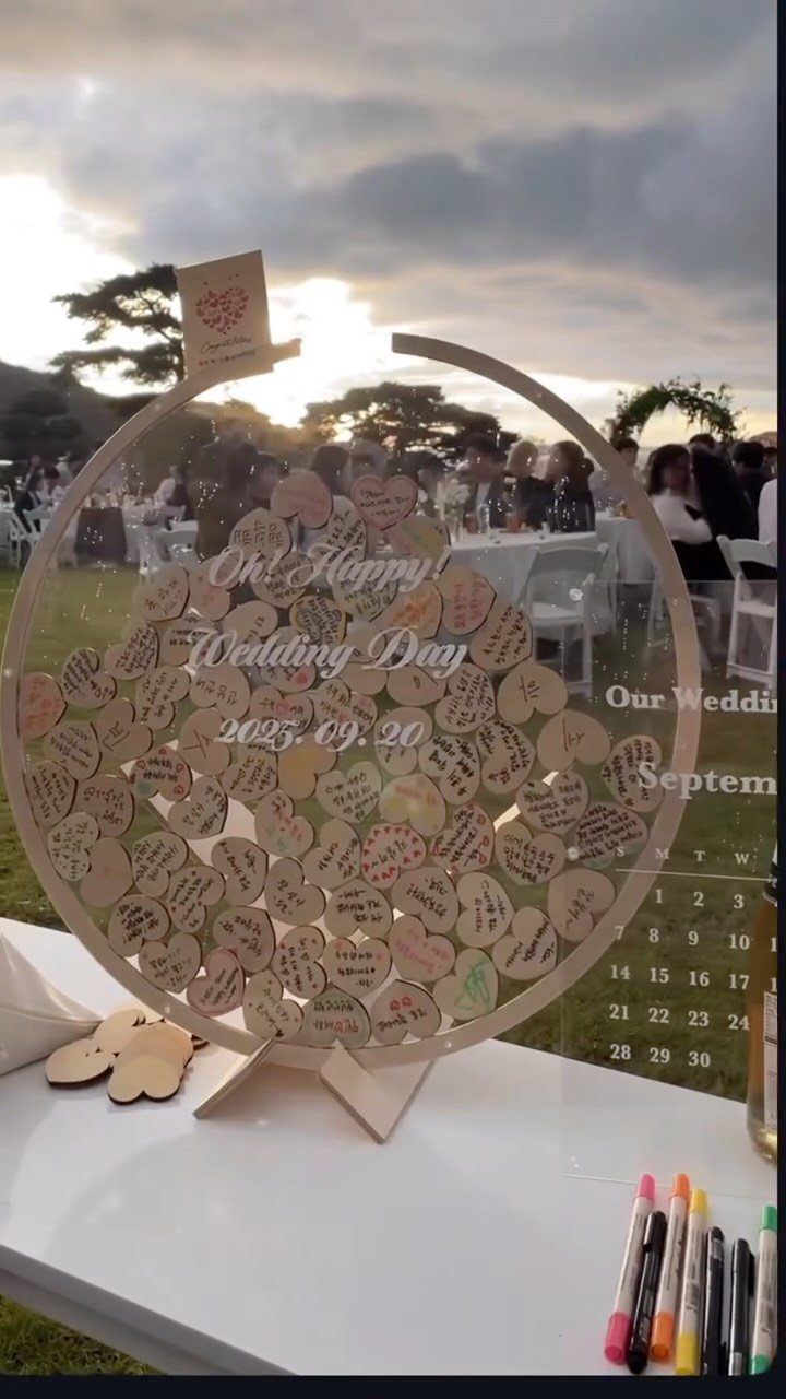 Circular acrylic guest book filled with wooden hearts at a wedding reception.