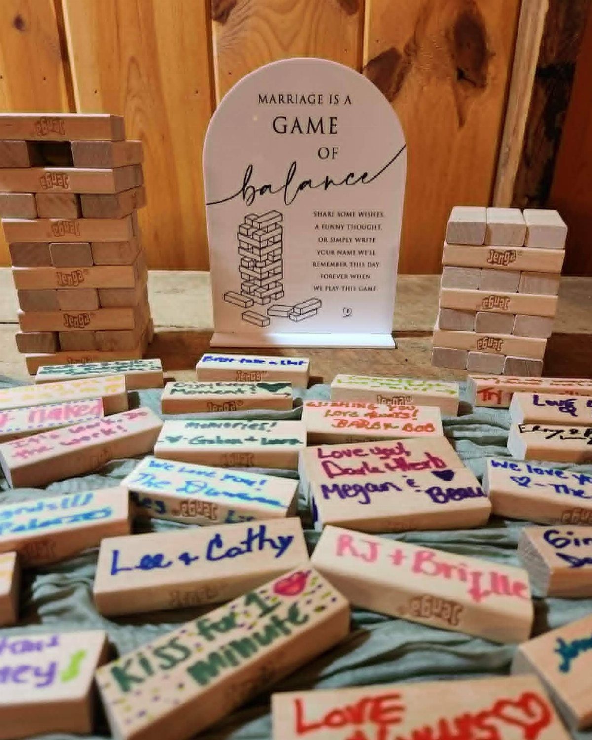 Wooden Jenga blocks with handwritten guest messages and a marriage balance sign.