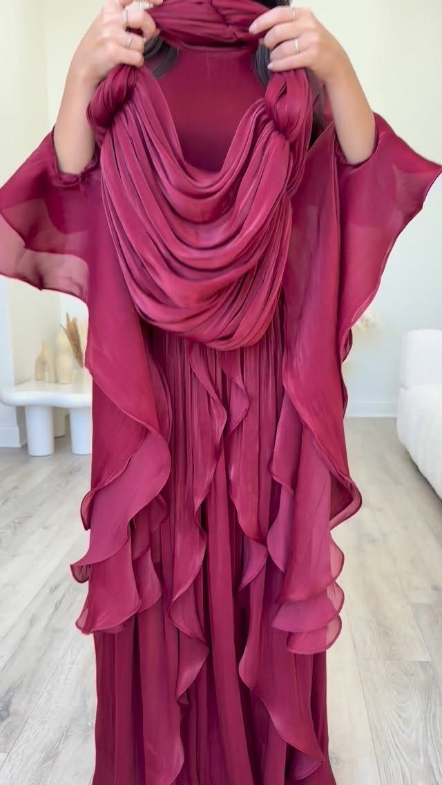 Deep red flowing gown with ruffled layers and a matching draped shawl.