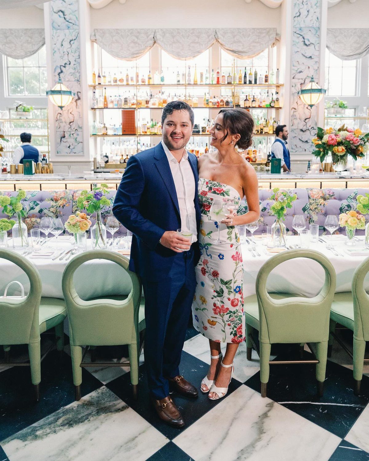 Couple posing in a restaurant, woman wearing a white floral midi dress.