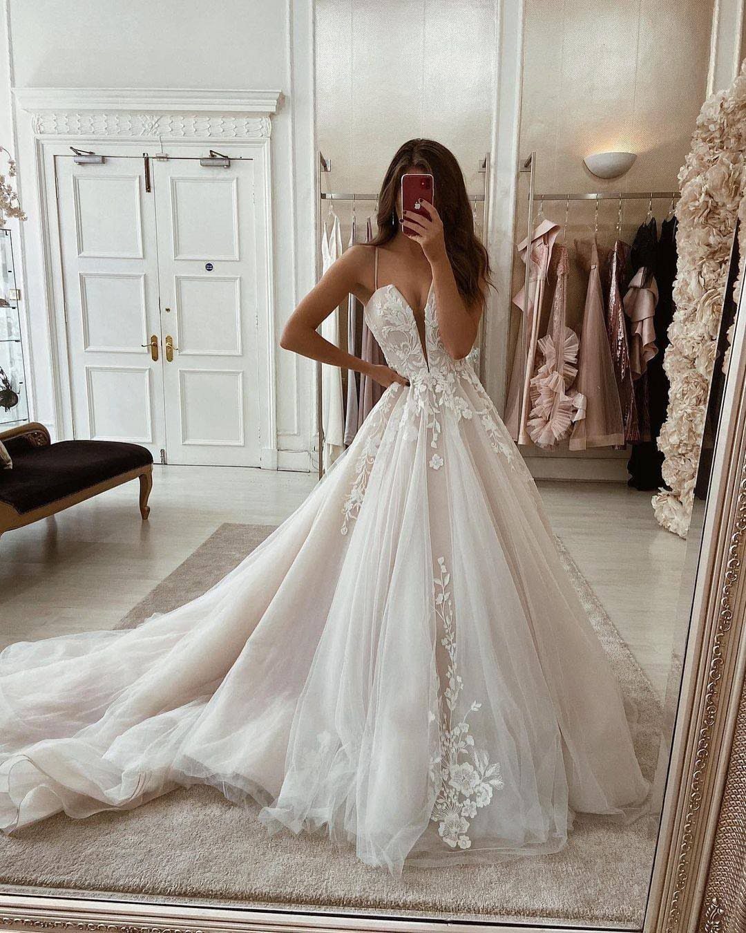 Woman in a voluminous champagne tulle wedding dress with lace appliques in a boutique