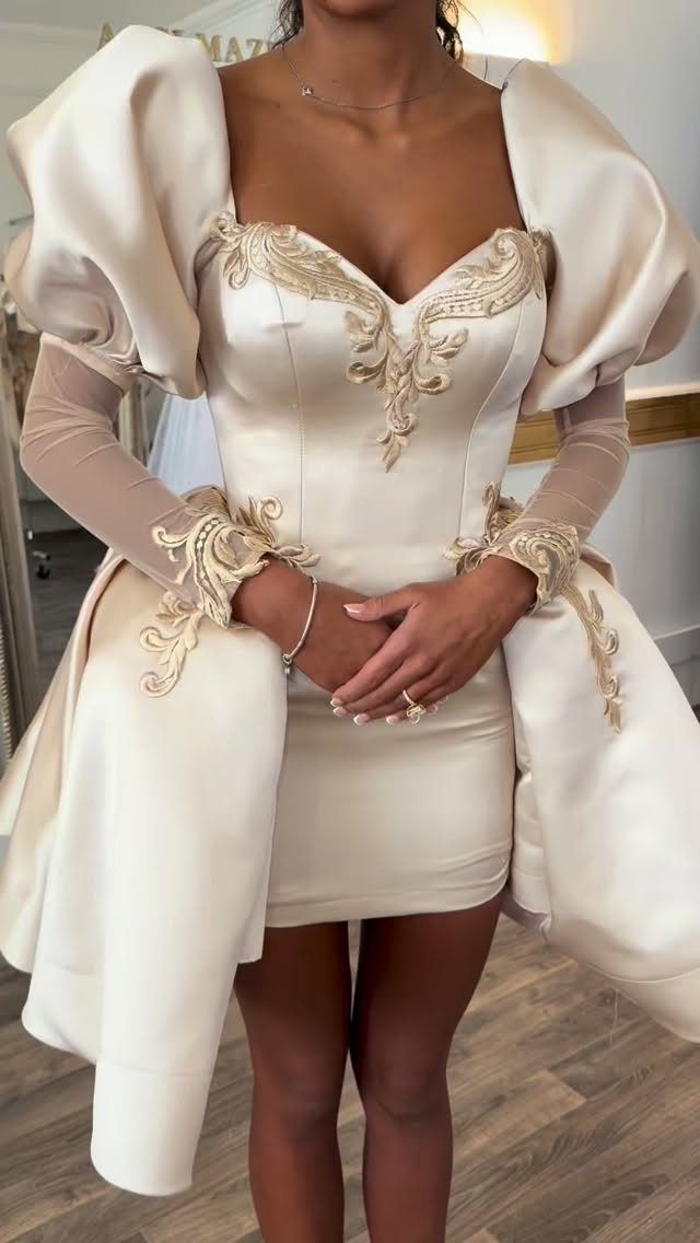 Woman wearing a short cream satin wedding dress with gold embroidery and puffed sleeves