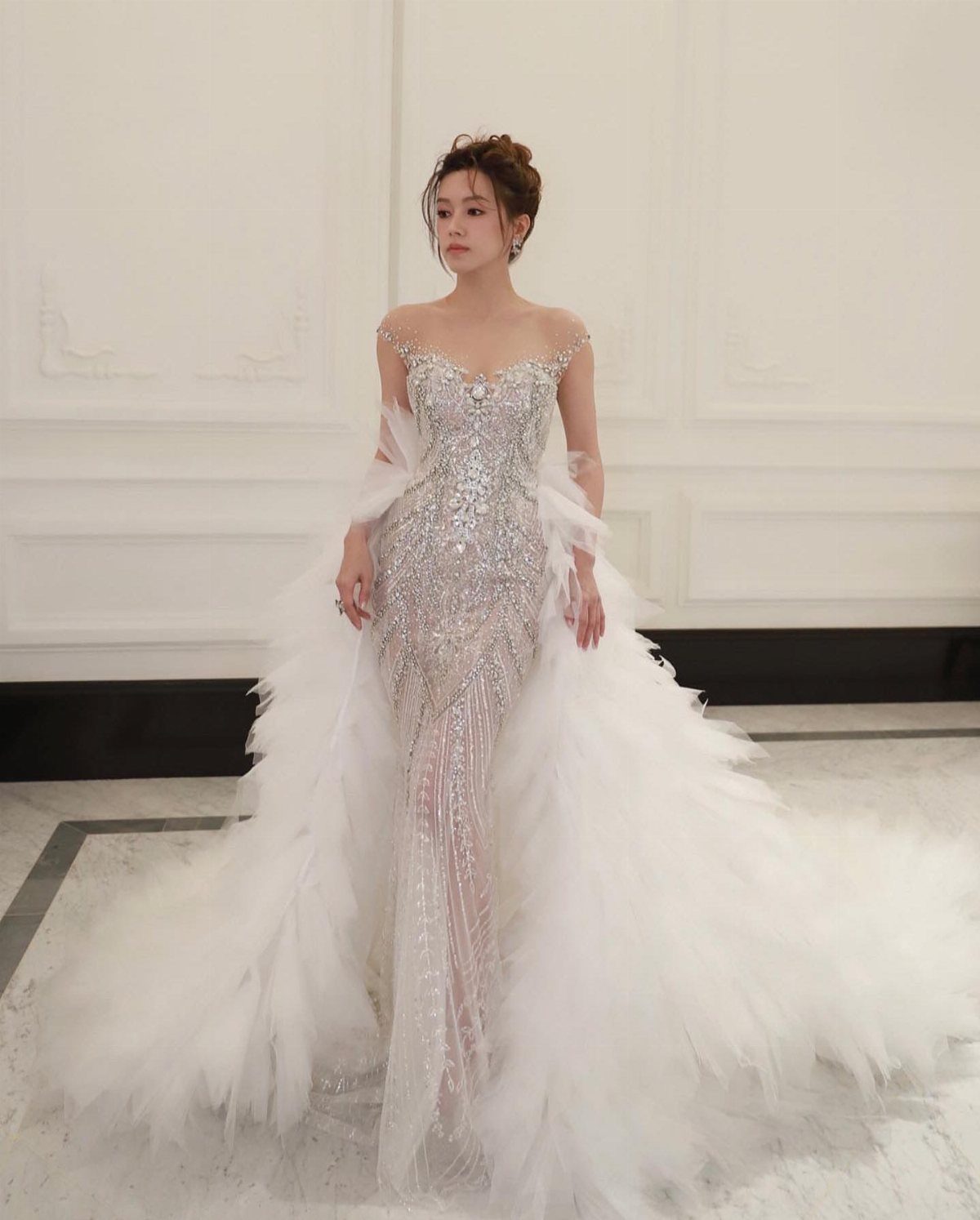 Woman in a sparkling white mermaid wedding dress with a voluminous ruffled tulle train.