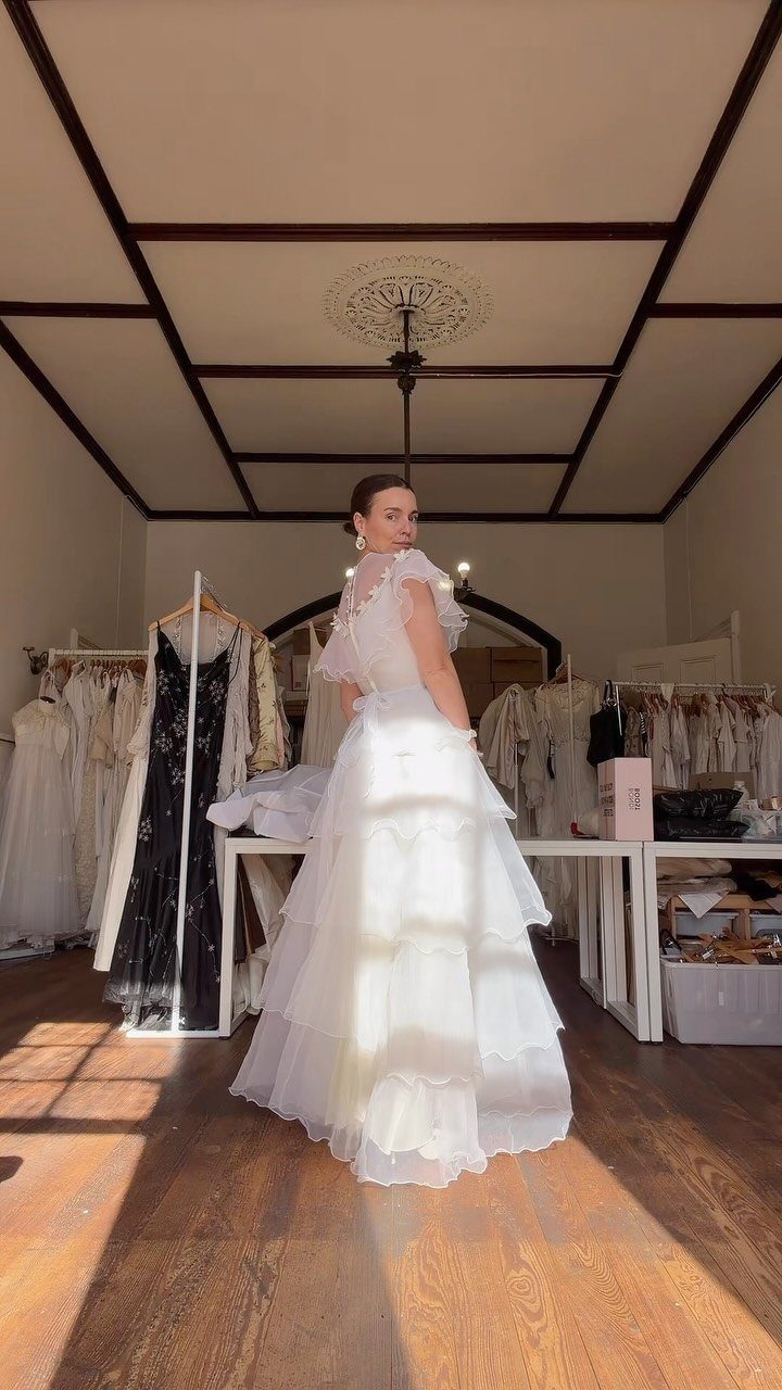 Woman in a white tiered ruffle wedding dress posing in a bridal boutique