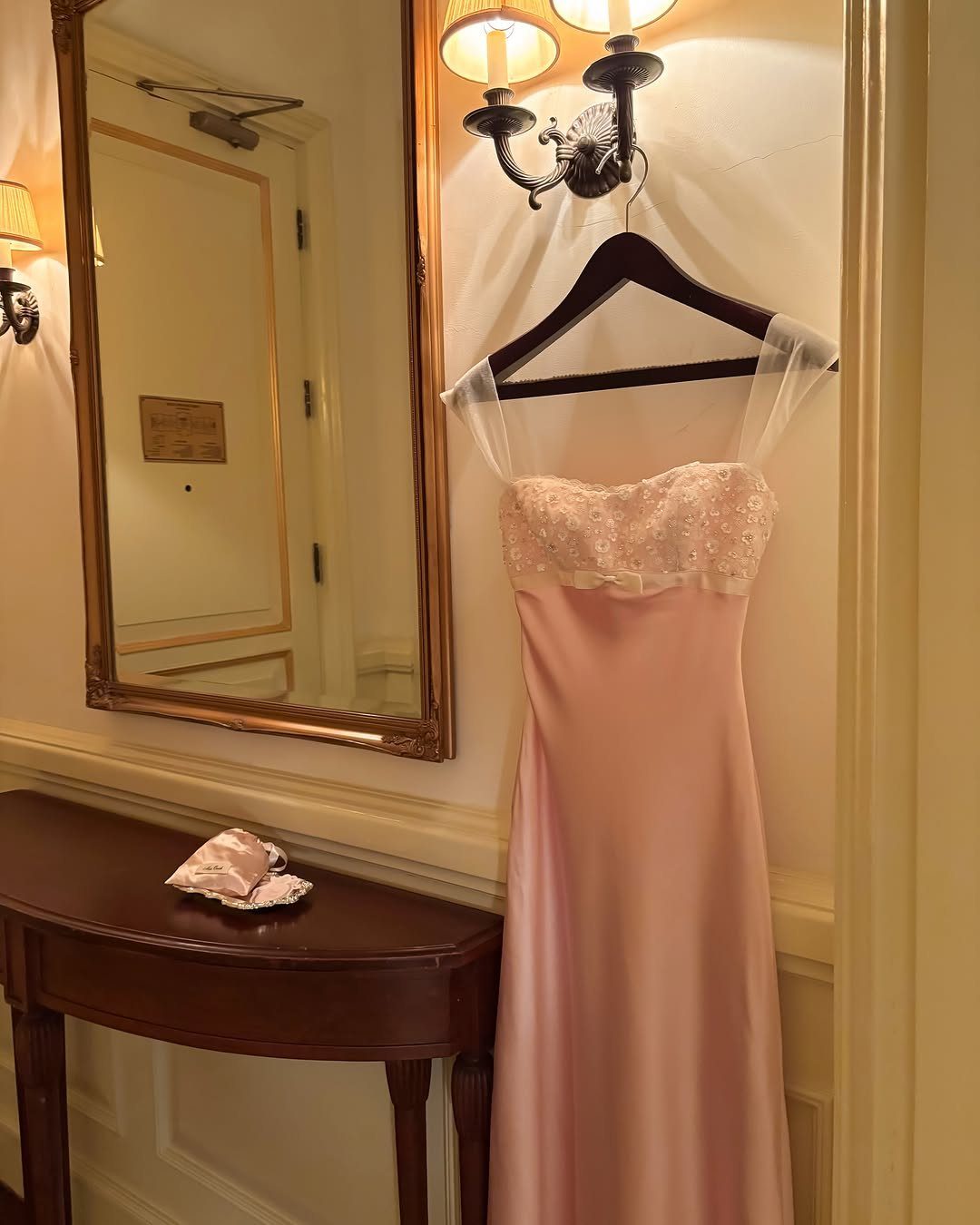 Light pink satin gown with lace bodice hanging on a black hanger.