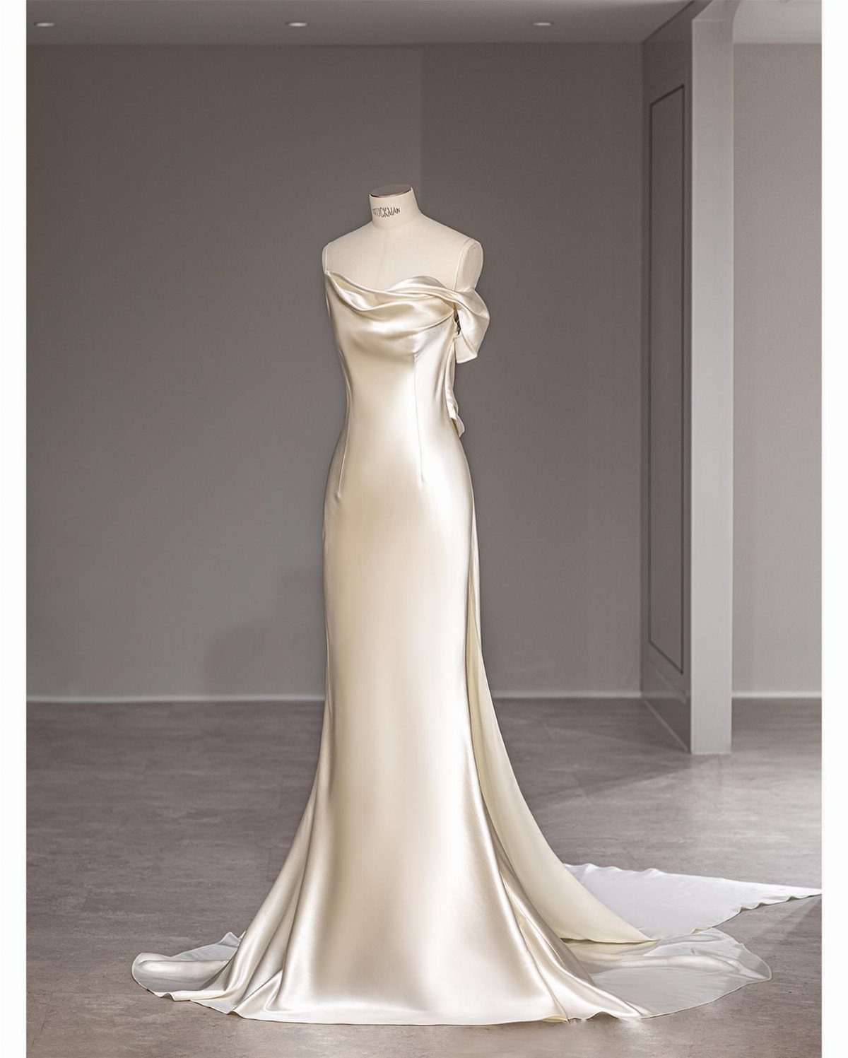 Champagne satin wedding gown on a mannequin with a glossy smooth finish.