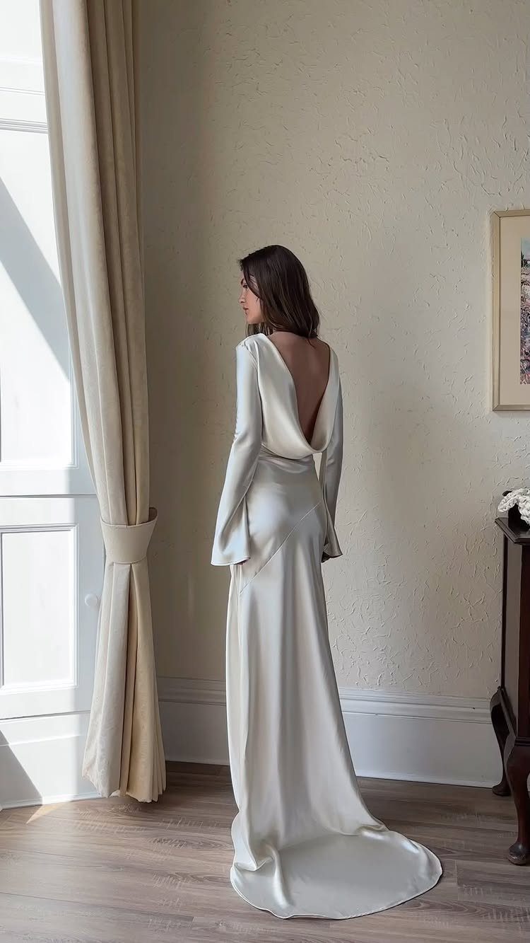 Woman wearing a long white silk wedding dress with a deep open back.