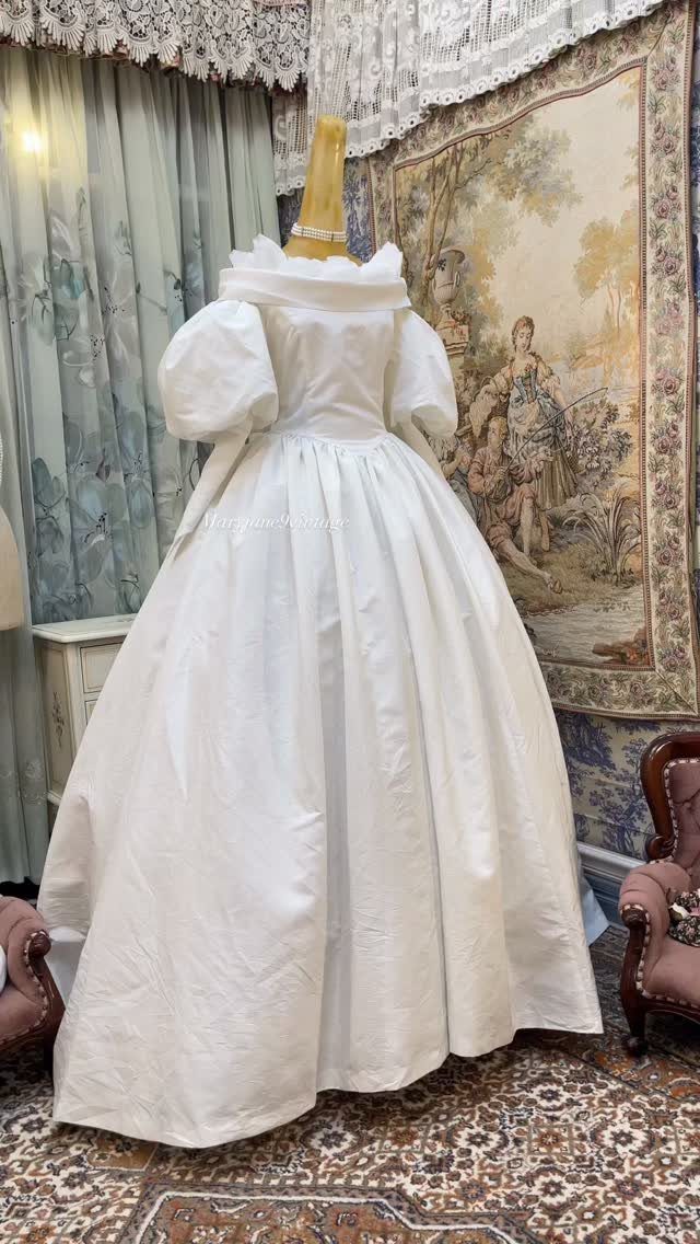 White silk wedding dress with puffed sleeves on a mannequin in a room