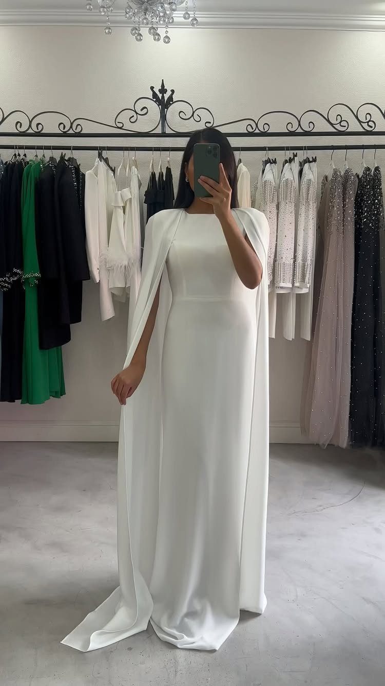 Woman in a white silk bridal gown with a cape in a boutique