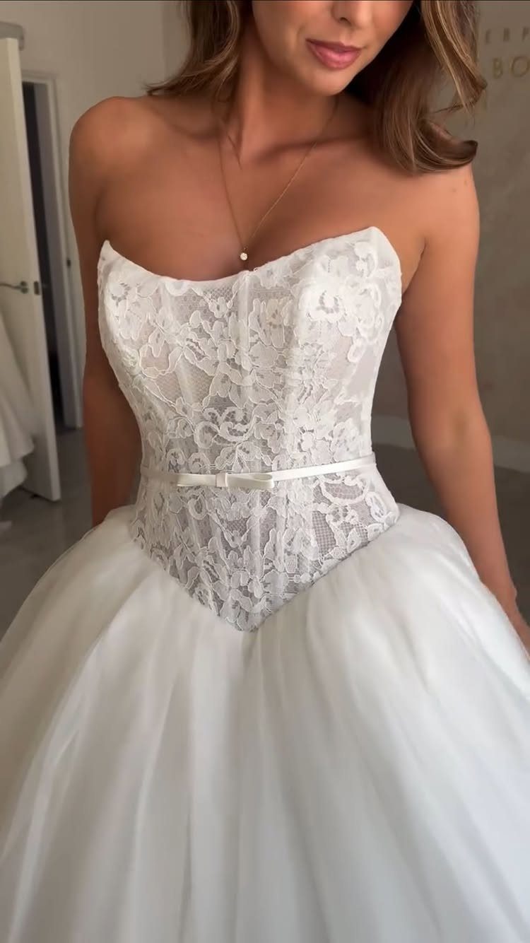 Woman wearing a white strapless wedding dress with a lace corset bodice and tulle skirt