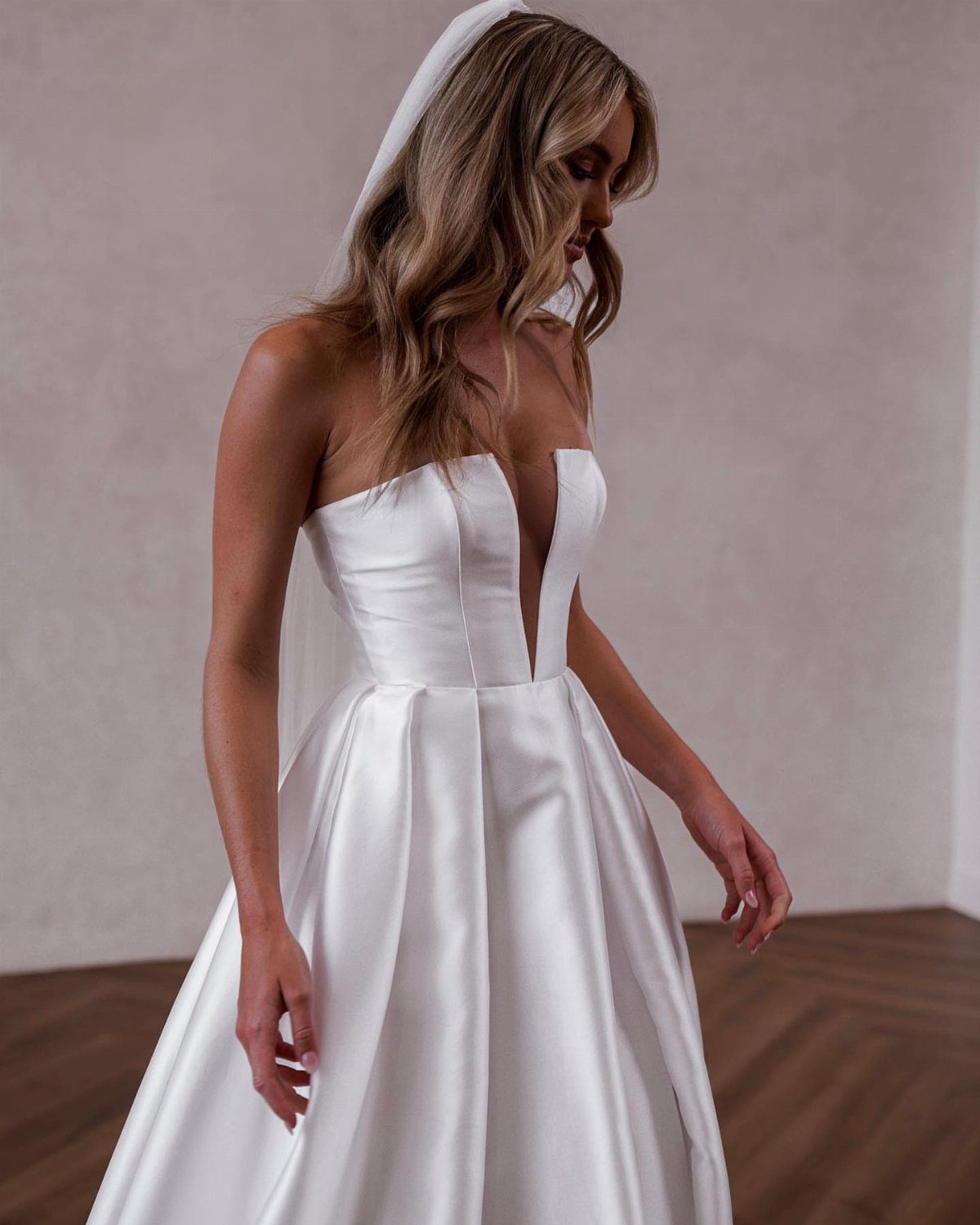 Woman in a white strapless wedding dress with a veil and deep neckline.