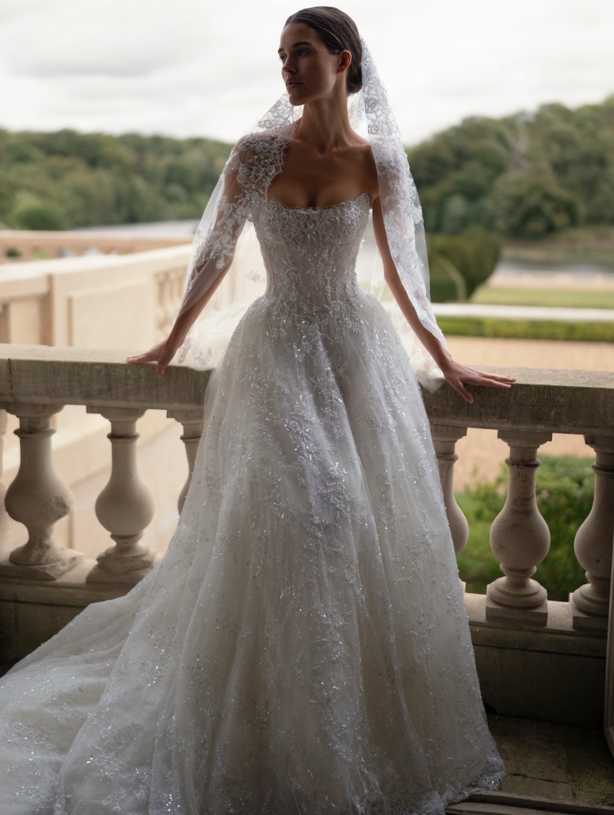Woman in a sparkling white strapless princess ball gown and lace veil on balcony
