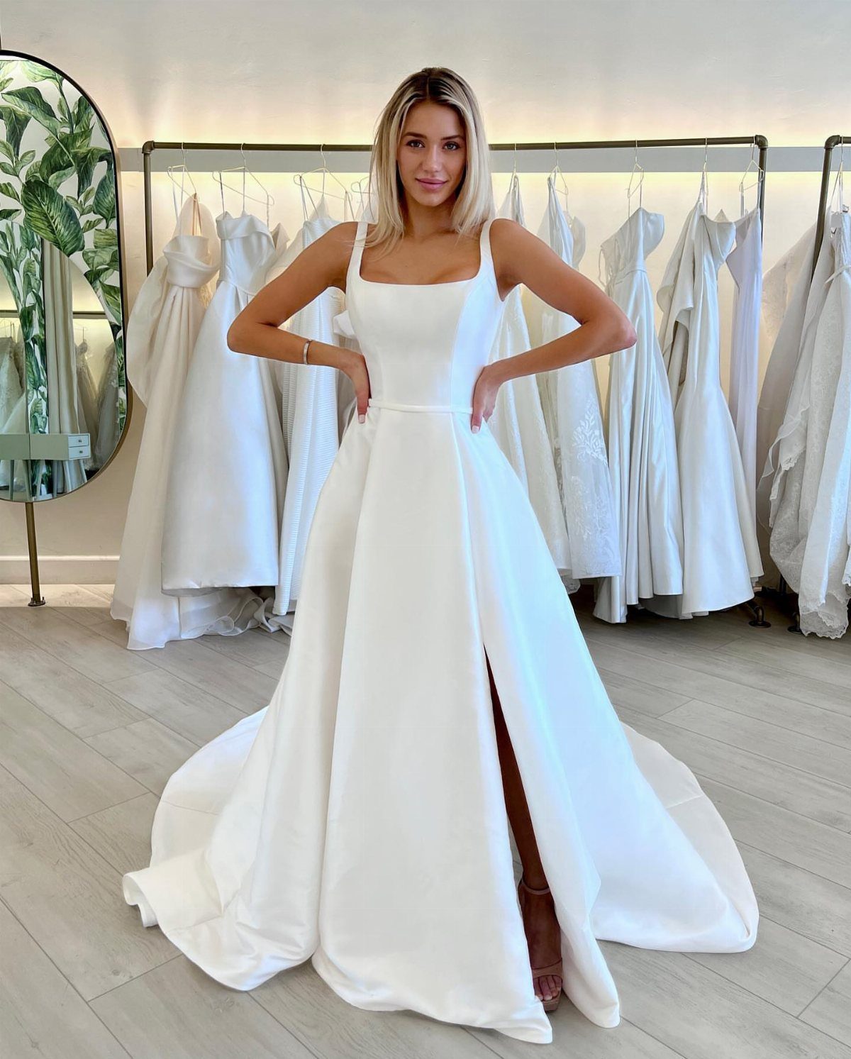 Woman wearing a white sleeveless wedding dress with a slit in a bridal shop