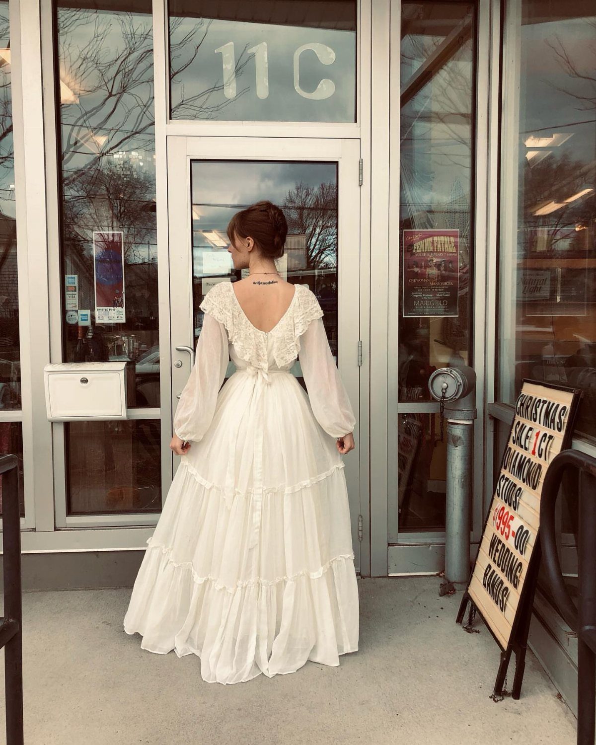 Woman from behind wearing a flowing white 1970s style vintage wedding dress