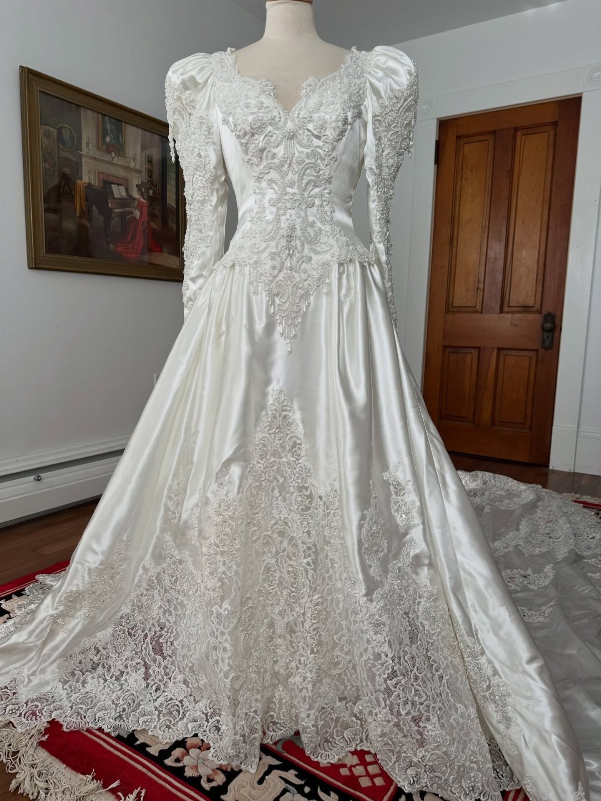 White satin vintage wedding dress with lace embroidery on a mannequin