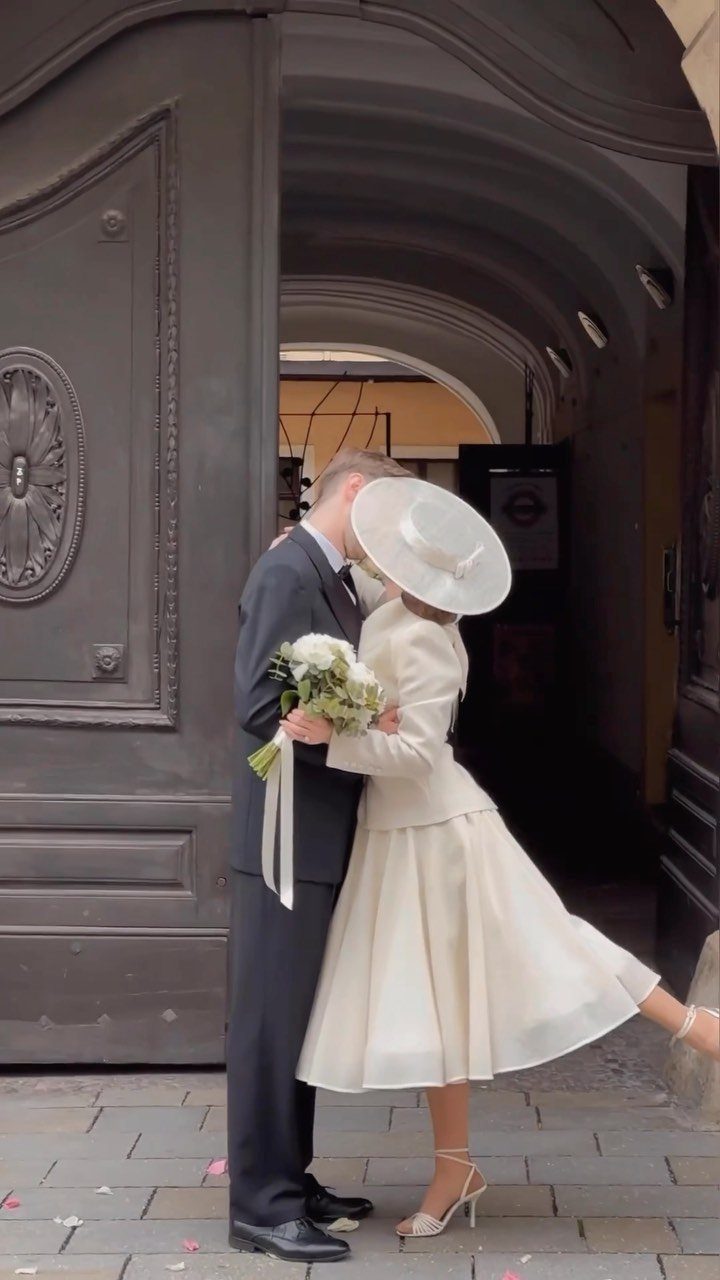 Couple kissing in a doorway, woman wearing a vintage cream tea-length wedding dress