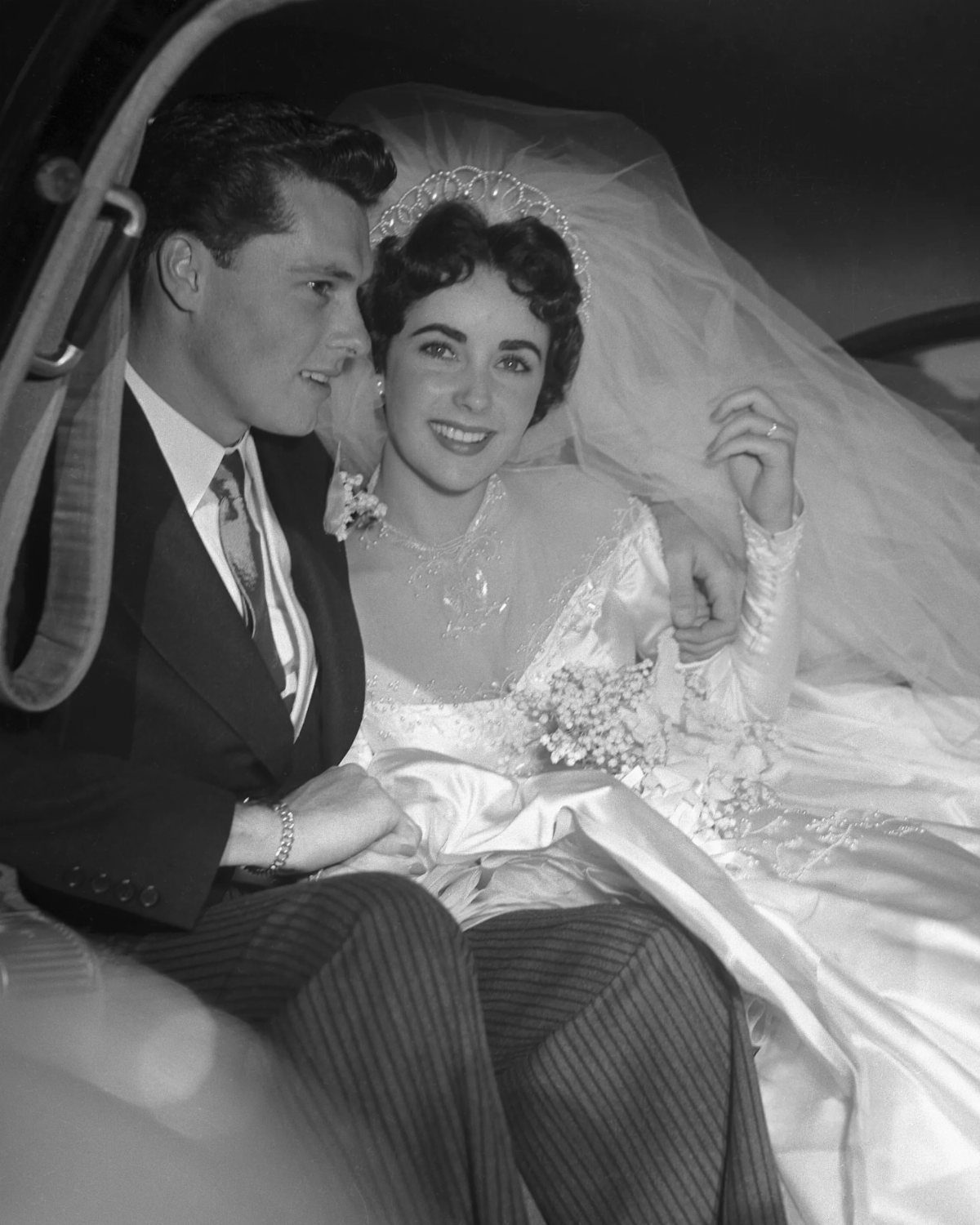 Bride and groom in a car, bride wearing a vintage satin wedding dress.