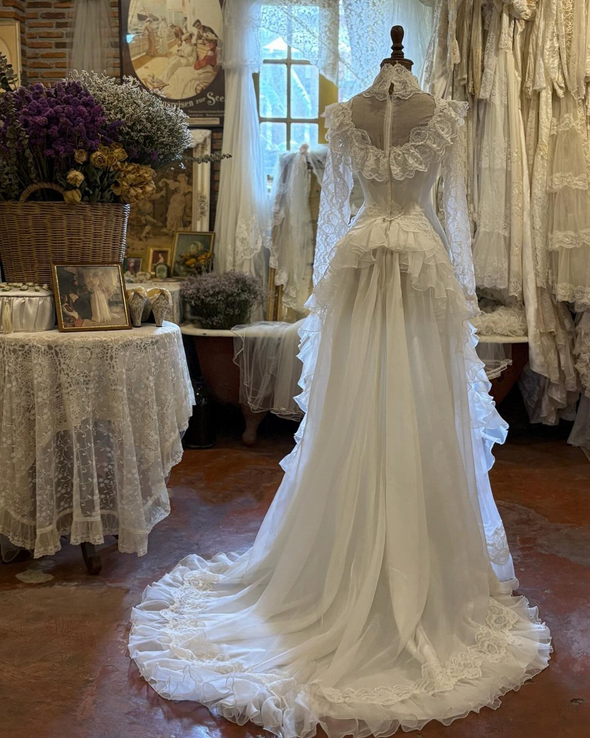 White vintage wedding dress with lace and a long train on a mannequin