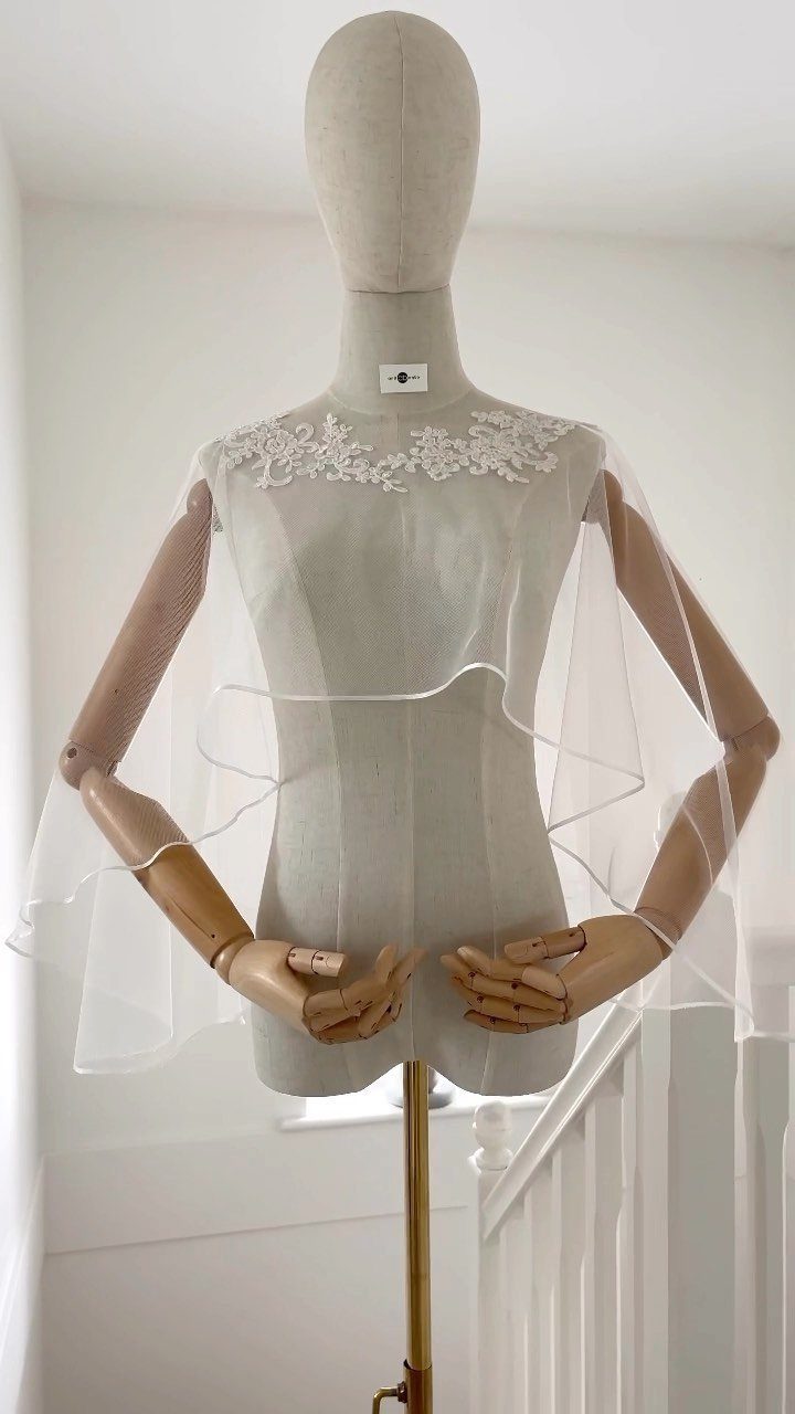 White sheer bridal bolero with floral lace neckline on a beige mannequin