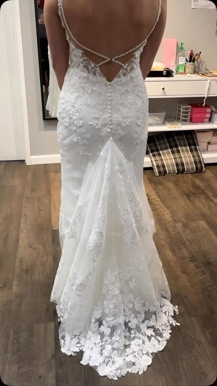 White lace wedding dress with a bustle lifting the train from behind.