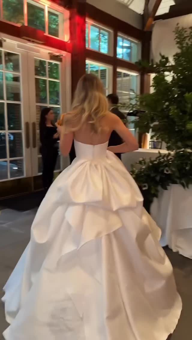 Woman from behind wearing a white wedding dress with a tiered bustle