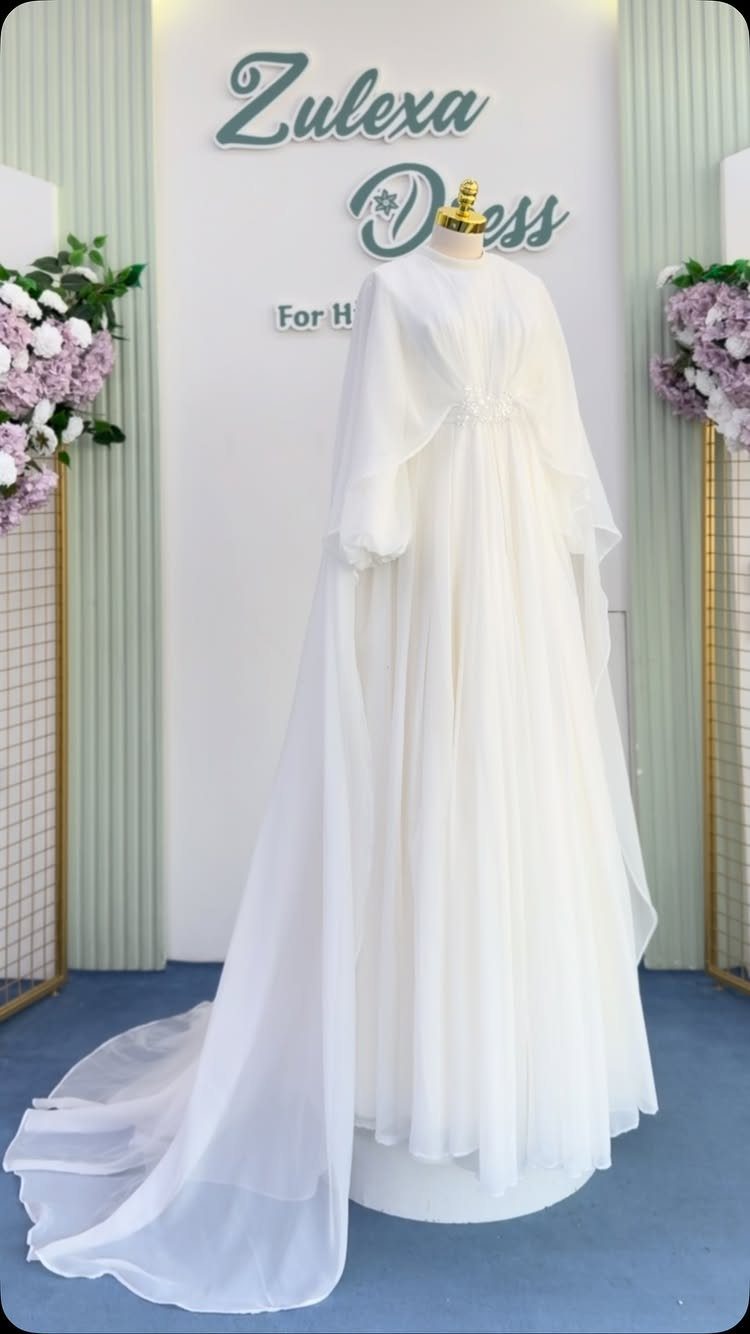 White chiffon wedding dress on a mannequin with a long flowing train.