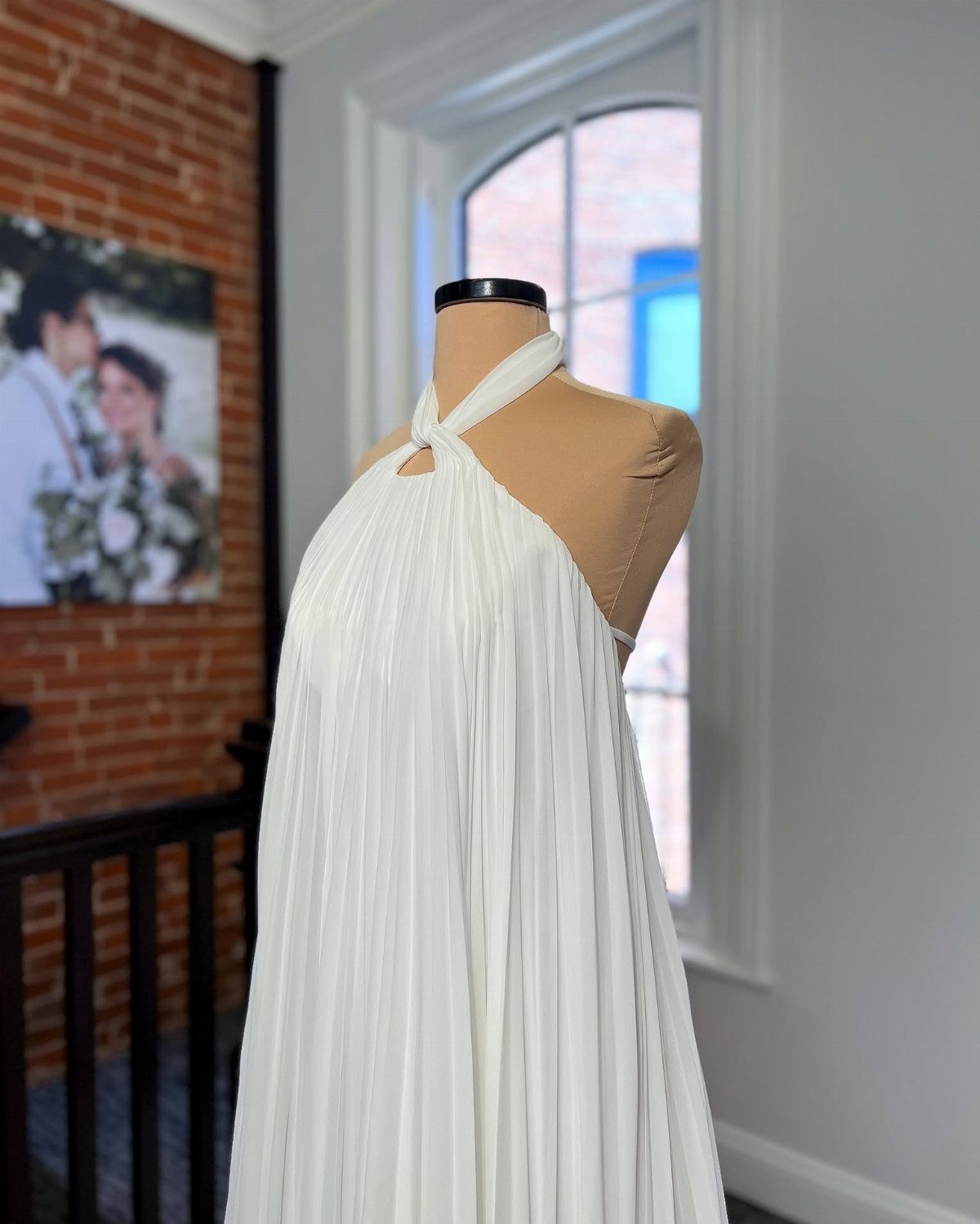 White pleated chiffon wedding dress with halter neck on a tan mannequin