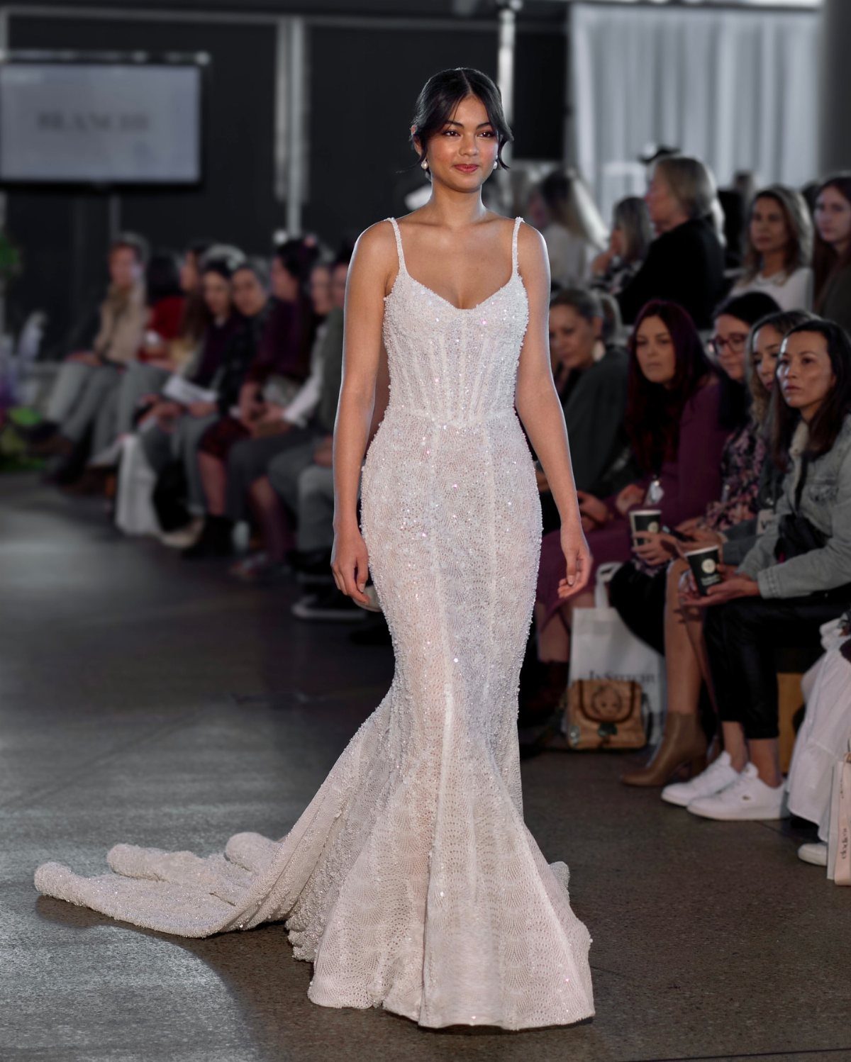 Model wearing a beaded white couture wedding gown walking a fashion runway