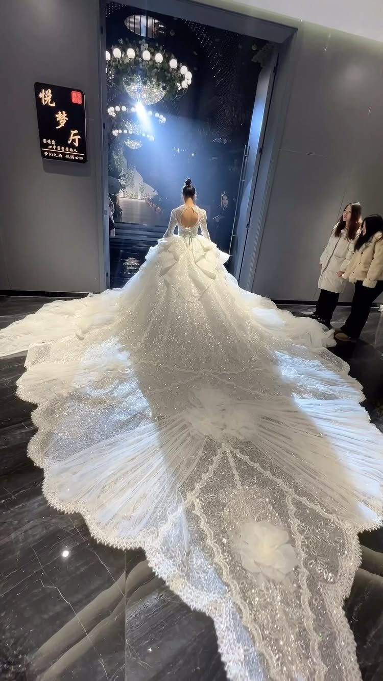 Woman wearing a white couture wedding dress with a massive, shimmering embroidered train.
