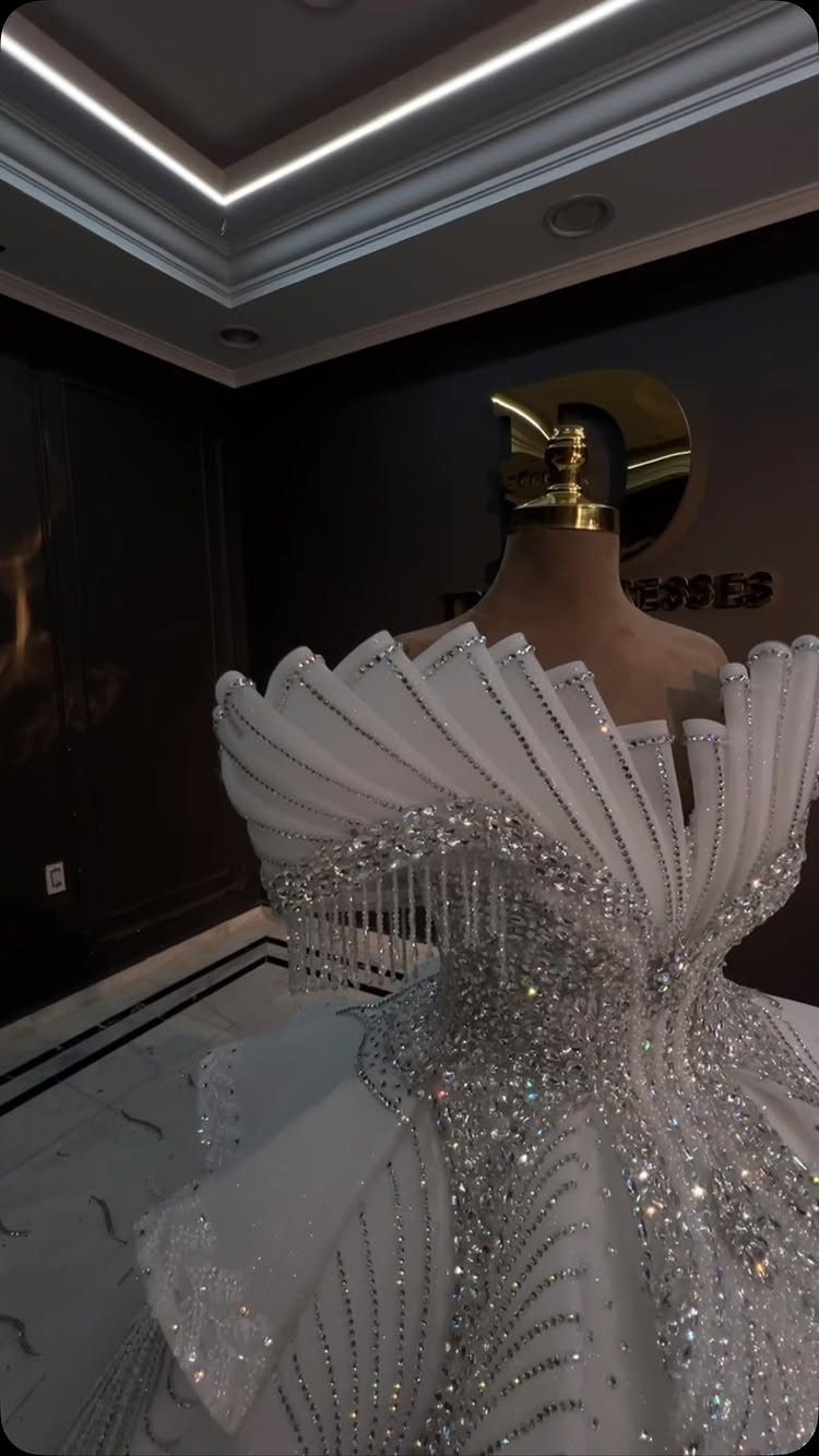 White couture wedding dress with architectural pleats and silver bead embellishments on mannequin