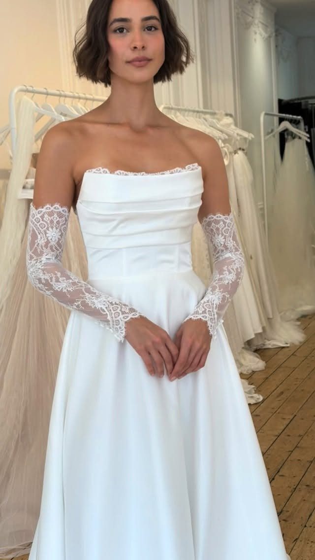 Woman wearing a strapless white wedding dress with separate lace sleeves in a boutique