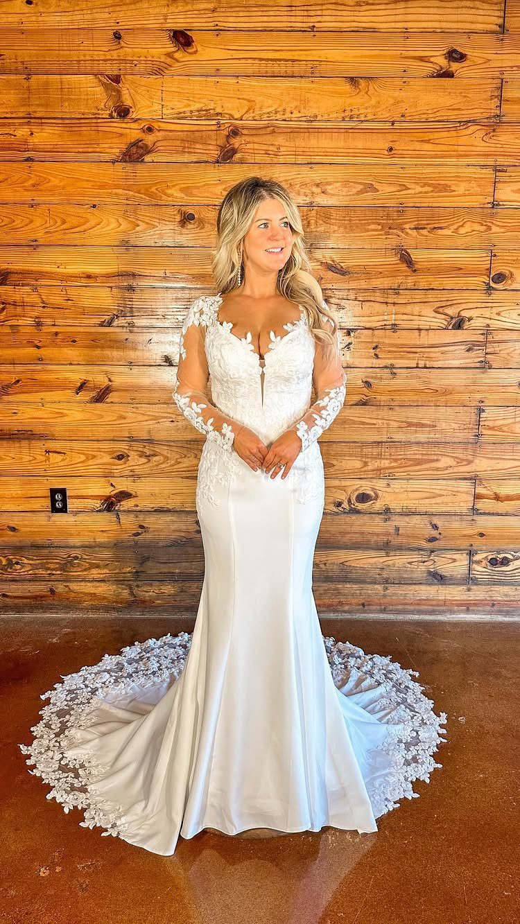 Woman in a white wedding dress with long lace sleeves and a train.