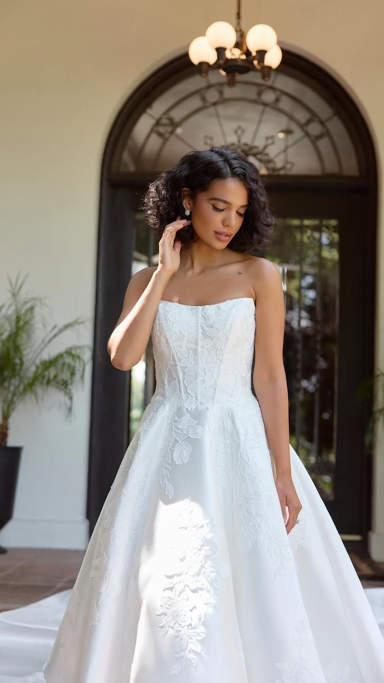 Woman in a strapless white wedding dress with textured floral fabric patterns.