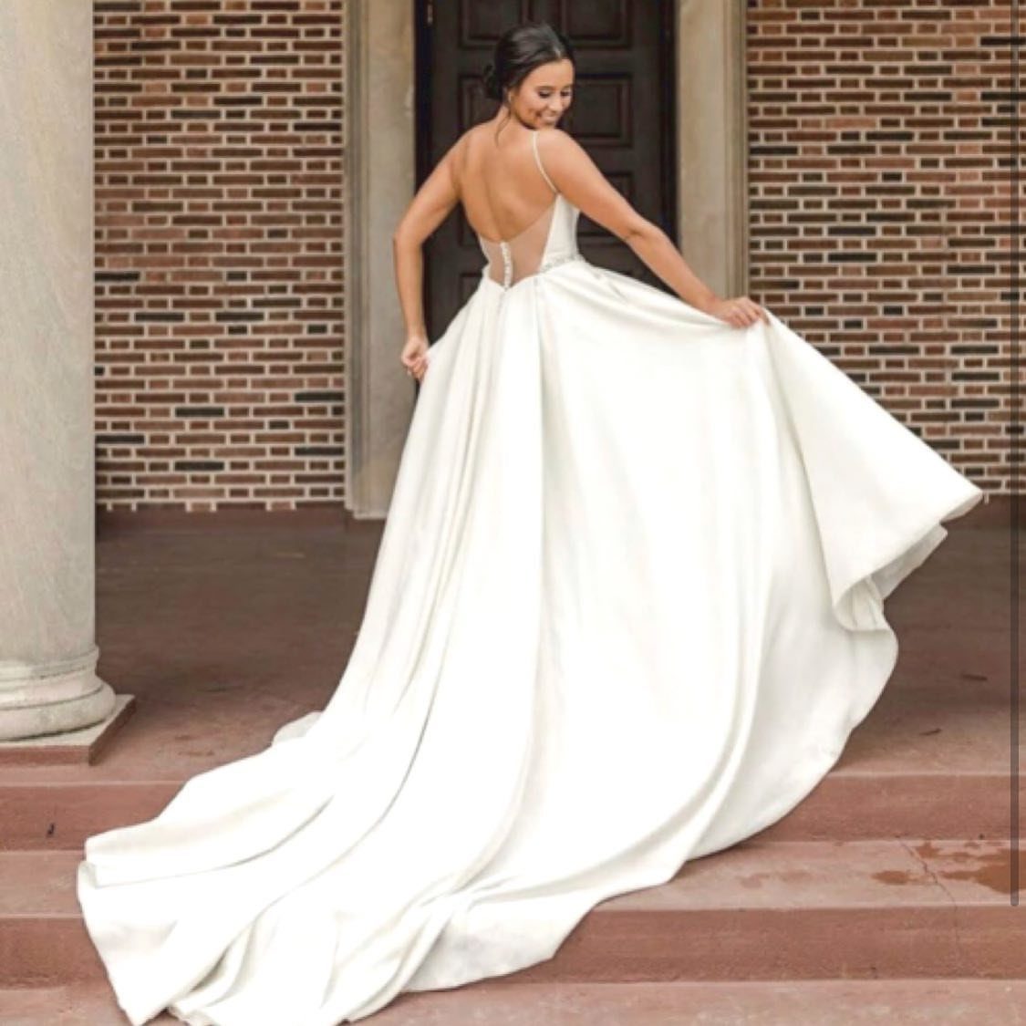 Woman in a white wedding dress with a full skirt posing on steps.