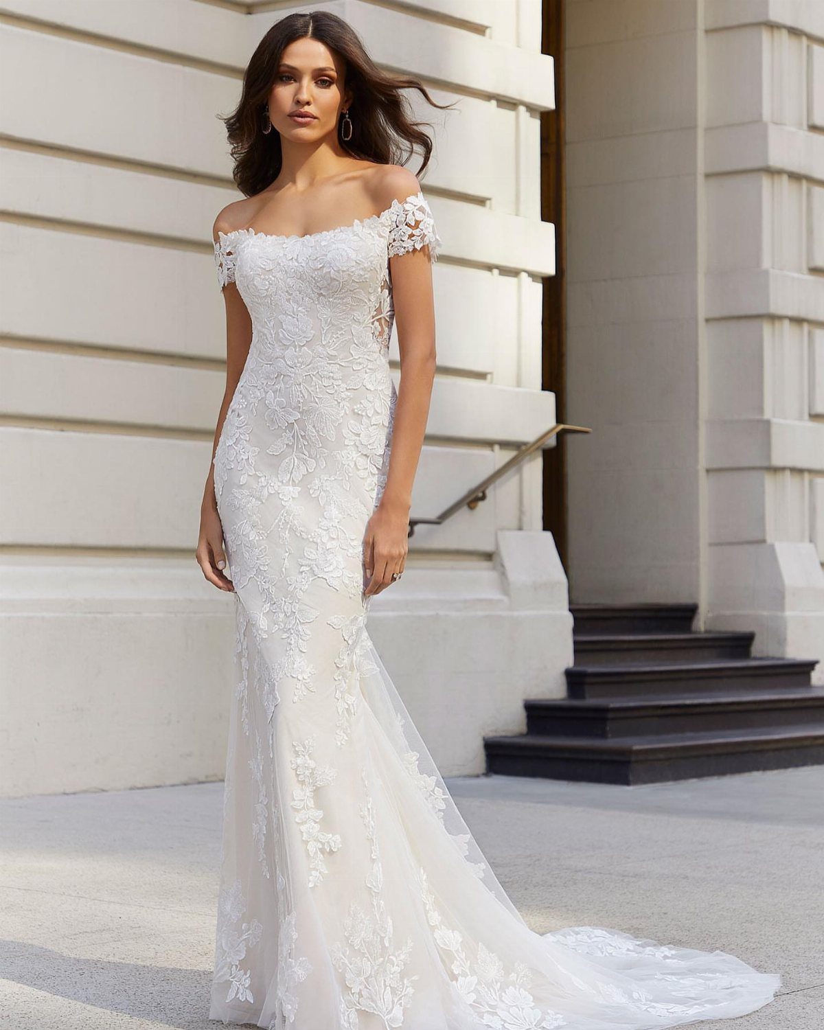 Woman in a white off-the-shoulder lace wedding dress with a mermaid silhouette.
