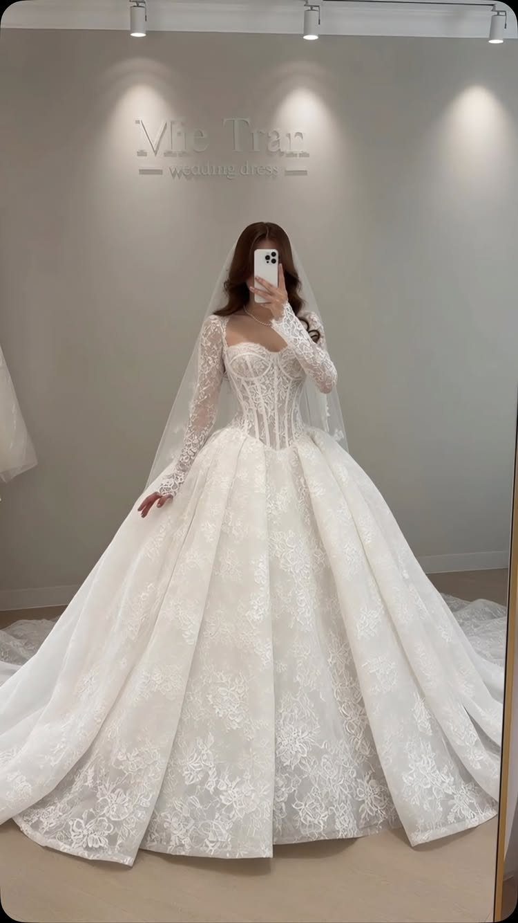 Woman in a white lace ballgown wedding dress with a full skirt and veil.