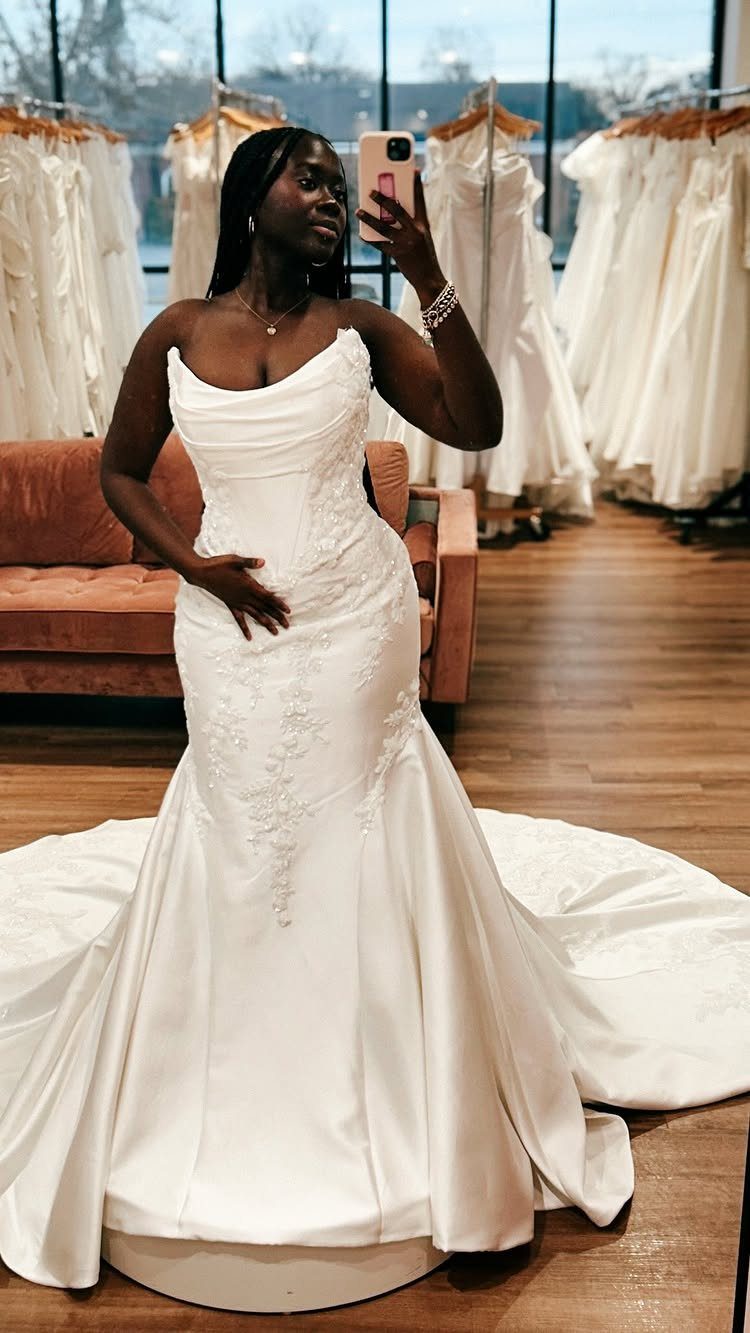 Woman in a white mermaid wedding dress with lace details taking a mirror selfie.