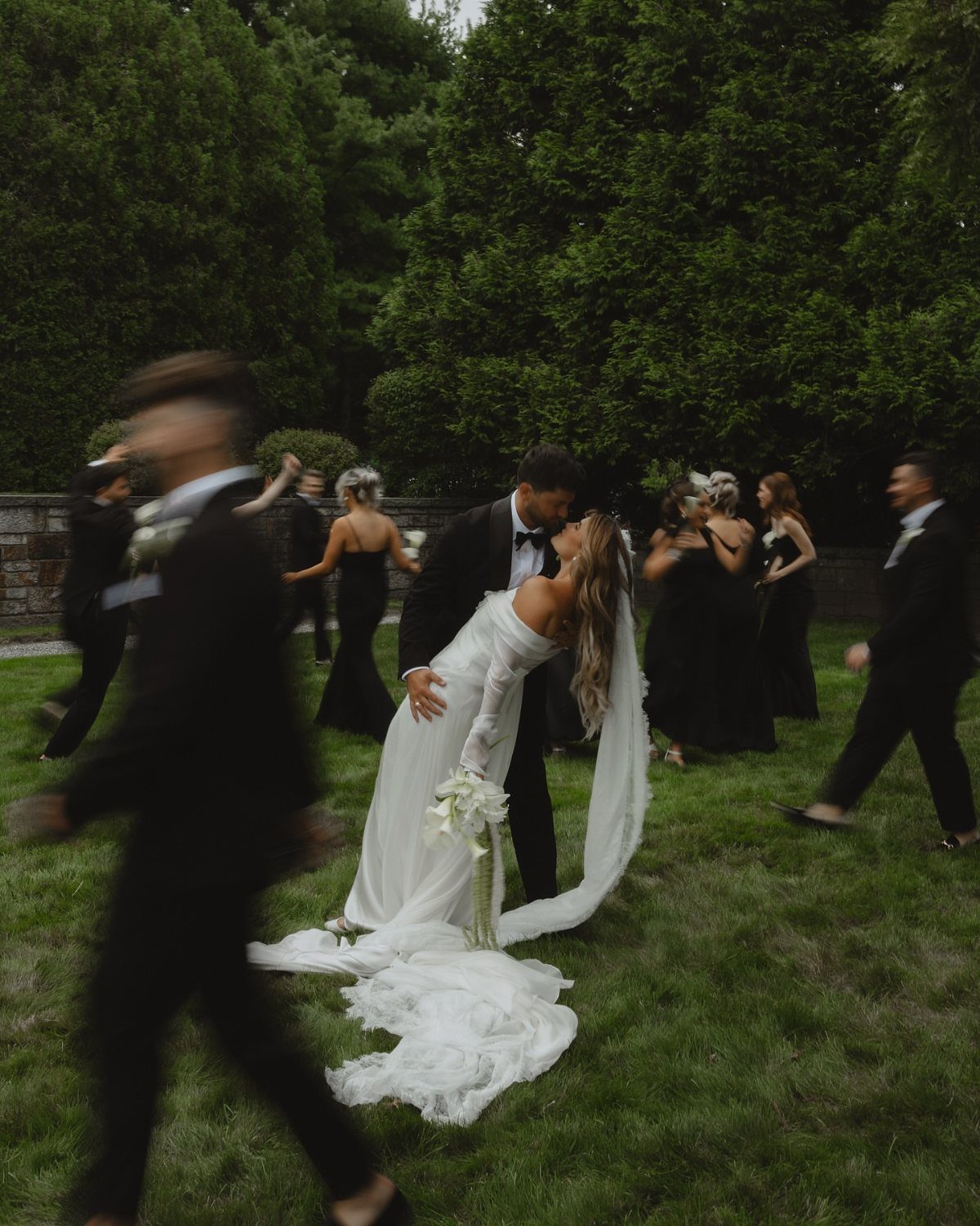 Bride in white gown being dipped by groom on a green lawn