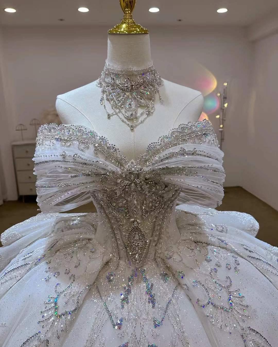 Ornate white wedding dress with silver sequins and beadwork on a white mannequin