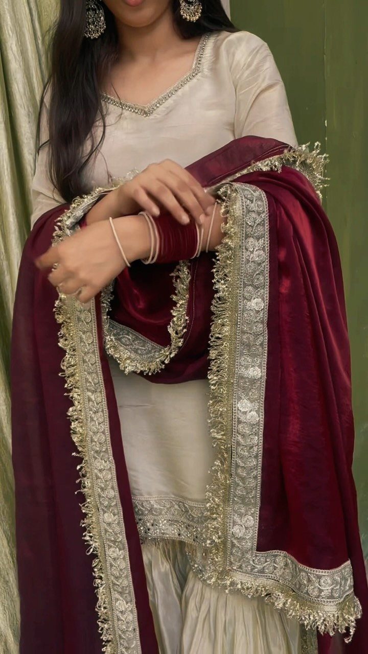 Woman wearing a cream traditional outfit with a red velvet embroidered shawl